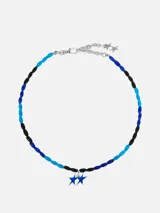Collar corto de cuentas de colores azul claro, azul oscuro y negro, con dije de dos estrellas azules y cierre de mosquetón plateado.