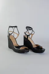 Sandalias de plataforma con taco corrido revestido en yute, confeccionadas en cuero color lila. Presentan diseño de puntera abierta y tiras largas para atar alrededor del tobillo.