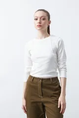 Remera de manga larga color blanco, de calce entallado, con cuello redondo a la base y costuras verticales decorativas que estilizan la silueta.