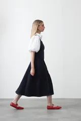 Vestido midi sin mangas de color azul oscuro, con escote cuadrado y silueta evasé. Presenta costuras a contratono en color blanco que recorren verticalmente el diseño, aportando estructura y un detalle gráfico. Confeccionado en tejido con cuerpo y caída firme.