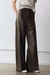 Pantalón de tiro alto confeccionado en tejido efecto piel, con diseño de pierna ancha y costuras marcadas en el delantero. Presenta cintura con trabillas, cierre frontal con cremallera, botón y gancho metálico, y bolsillos de plastrón en la espalda.