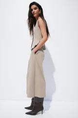 Pantalón sastrero de corte cropped y tiro alto, con piernas amplias y pliegues frontales. Presenta cierre con botón y trabillas en la cintura, en un tono beige con estampado de microcuadros.