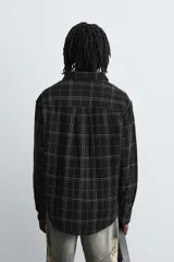 Sobrecamisa de corte relajado confeccionada en tejido de algodón, con diseño a cuadros, cuello solapa, cierre frontal de botones y bolsillo en el pecho.