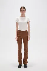 Pantalon de corte flare en color negro, con acabado engomado, tiro medio y cierre frontal con botón y cremallera.