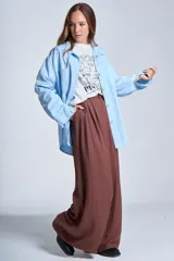 Sobrecamisa color beige confeccionada en gabardina, de corte holgado, con cuello camisero, cierre frontal con botones, dos bolsillos de parche en el pecho y mangas largas con puños abotonados.