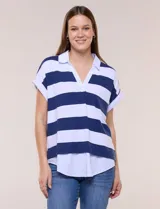 Remera holgada con diseño two-fold que simula efecto superpuesto con una camisa blanca inferior. Presenta cuello polo, escote en V y rayas horizontales beige y blancas.