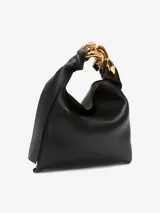 Bolso de mano JW Anderson modelo Chain Hobo Small, color negro, confeccionado en cuero. Presenta cierre magnético, logo en relieve, asa con cadena decorativa en tono dorado y un compartimento interno.