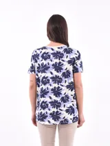 Remera de mangas cortas con estampado de flores abstractas en tonos azul y lila sobre fondo blanco.