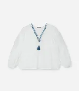 Blusa color blanco con escote en pico con bordado de corazones azules, mangas largas con puños elásticos, lazos con borlas y detalle de hilo metalizado.