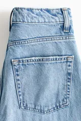 Jean barrel de tiro alto confeccionado en denim de algodón rígido, con diseño curvo y voluminoso en las piernas, largo tobillero y cinco bolsillos. Cuenta con cierre de botones en el frente.