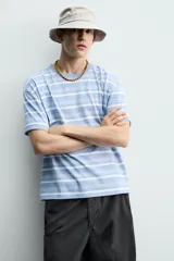 Remera relaxed fit con diseño de rayas horizontales en tonos celestes y blancos, cuello redondo y manga corta, con efecto lavado.