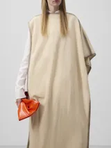 Bolso de mano acolchado de efecto charol color naranja quemado, con forma rectangular y asa larga ajustable y extraíble. Presenta un cierre magnético y el logo grabado en la parte inferior central.