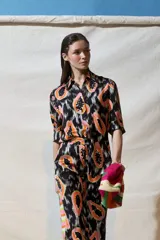 Camisa de manga corta con estampado de papayas en tonos naranja y rosa sobre fondo negro.