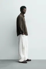 Camisa de corte regular fit confeccionada en tejido de algodón con diseño de rayas verticales. Presenta cuello abotonado, manga larga con puños abotonados, bolsillo plastrón en el pecho y cierre frontal con botones.