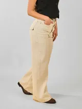 Pantalón jean color beige, de corte ancho y tiro alto, con bolsillos delanteros y traseros.