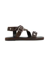 Sandalias planas de cuero marrón con tiras decoradas con tachas metálicas redondas y hebilla de ajuste lateral.