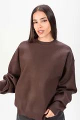 Sweater de punto color marrón, de corte oversize, con cuello redondo y mangas largas con puños ajustados.