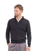 Buzo de punto color negro con cuello alto y cierre frontal parcial, de manga larga con puños y ruedo acanalados.