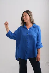 Camisa de lino en color azul francia, con corte holgado, cuello clásico, cierre frontal con botones de nácar y bolsillo en el pecho. Presenta mangas largas con sistema de ajuste mediante trabilla y botón.