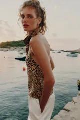 Top halter satinado con estampado de leopardo, cuello desbocado y espalda descubierta con cierre de botón en la nuca.