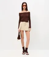 Short pollera beige de sarga con bolsillos cargo laterales y solapa, cintura ancha, pliegues delanteros y cierre frontal discreto.
