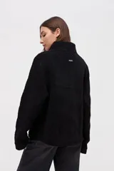 Buzo de sherpa con textura capitoneada, color bordó, con cuello alto y cierre frontal parcial. Presenta bolsillos laterales y calce relajado.