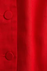 Vestido corto sin mangas color rojo, con cuello redondo y cierre frontal de botones. Presenta pinzas moldeadoras y bolsillos delanteros decorativos con solapa.