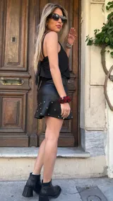 Minifalda negra de cuero sintético con volados y tachas plateadas.