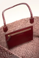 Cartera tote de cuero vacuno trenzado a mano, color bordó, de diseño espacioso con asas firmes.