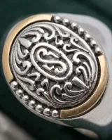 Anillo de plata y oro de diseño ovalado, con detalles grabados y filigrana en relieve en la parte superior.