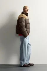 Cazadora puffer relaxed fit color marrón con canesú superior en tono tostado de acabado aterciopelado. Cuenta con cuello subido, manga larga, bolsillos de vivo en la cadera, acabados en elástico y cierre frontal con cremallera.