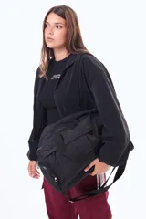 Bolso tipo shopper de nylon color negro, amplio y funcional. Cuenta con cierre superior, asas reforzadas para llevar al hombro y correa ajustable extraíble. Incluye bolsillos externos con cierre para mayor organización.