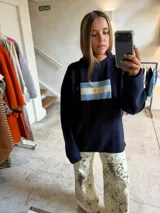 Sweater oversize gris de punto con hombros caídos y diseño de la bandera de Argentina bordado en el centro del pecho.