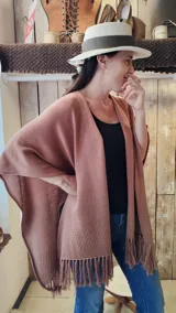 Ruana de hilo de algodón color beige con terminación de flecos en los extremos y pequeño detalle de etiqueta lateral.
