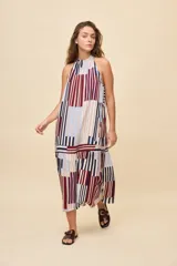 Vestido largo de silueta amplia y caída fluida, con escote halter fruncido y falda con recorte. Presenta diseño geométrico multicolor a rayas en tonos bordó, azul, celeste y beige.