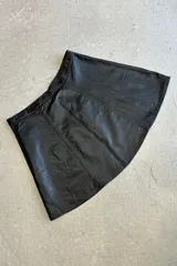 Minifalda negra de cuero con corte en A y costuras verticales decorativas.