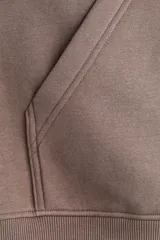 Campera con capucha de corte holgado, confeccionada en felpa con interior cepillado. Presenta cierre frontal, hombros caídos, bolsillos delanteros abiertos y terminaciones en punto acanalado en puños y bajo.