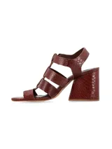 Sandalias de tacón alto ancho de líneas arquitectónicas, con diseño de tiras múltiples estilo cangrejera y cierre de hebilla metálica en el tobillo. Confeccionadas en cuero con estampado texturizado tipo cocodrilo color marrón chocolate.
