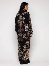 Pantalón de viscosa negro con estampado floral en tonos dorados, marrones y grises.