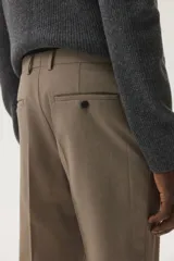 Pantalón de vestir color beige, de corte slim fit, con pinzas marcadas en el frente y dobladillo en el bajo.