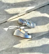 Sandalias de plataforma doradas, con suela ancha y tiras anchas cruzadas en el empeine y una tira ajustable en el tobillo.