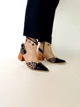 Bota tejana de cuero, combinada en color tostado, animal print de leopardo y puntera en charol negro. Cuenta con taco de madera, detalle de hebilla lateral y ojales metálicos en la parte superior.