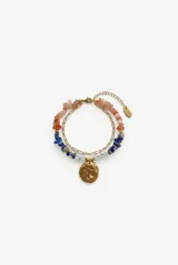 Pulsera doble dorada de acero con piedras naturales facetadas en tonos naranjas, azules y celestes, y un dije metálico redondo texturizado.