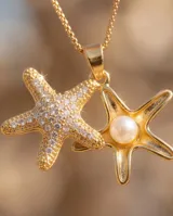 Collar de bronce con cadena fina y doble dije colgante en forma de estrella de mar, uno de ellos pavimentado con circonias y el otro con una perla central.