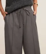 Pantalón de corte recto y estilo sastre, confeccionado en una mezcla de poliéster y viscosa. Presenta cintura alta con elástico y lazo ajustable, costuras frontales decorativas y bolsillos laterales.