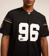 Remera deportiva negra de poliéster con tecnología Dry, cuello en V y manga corta. Estampado frontal con el número 96 y el logo de los Baltimore Ravens de la NFL.