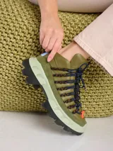 Zapatilla de cuero verde con caña alta, cordones elásticos y suela de goma de dos tonos.