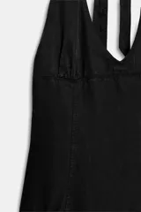 Vestido corto negro con cuello halter, escote en pico y falda con vuelo. Cuenta con tirantes para anudar al cuello y costuras visibles en el cuerpo.
