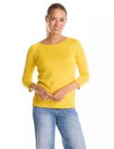 Buzo de tejido fino en color amarillo, con cuello redondo, manga raglán tres cuartos y detalle de tachas metálicas a lo largo de las mangas.