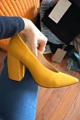 Zapatos de tacón alto en color mostaza, confeccionados en acabado gamuzado, con diseño de punta fina y taco ancho geométrico.